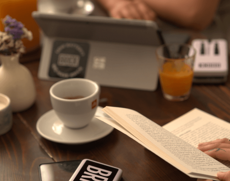 Frau liest ein Buch und lädt ihr Handy mit einem Brick auf