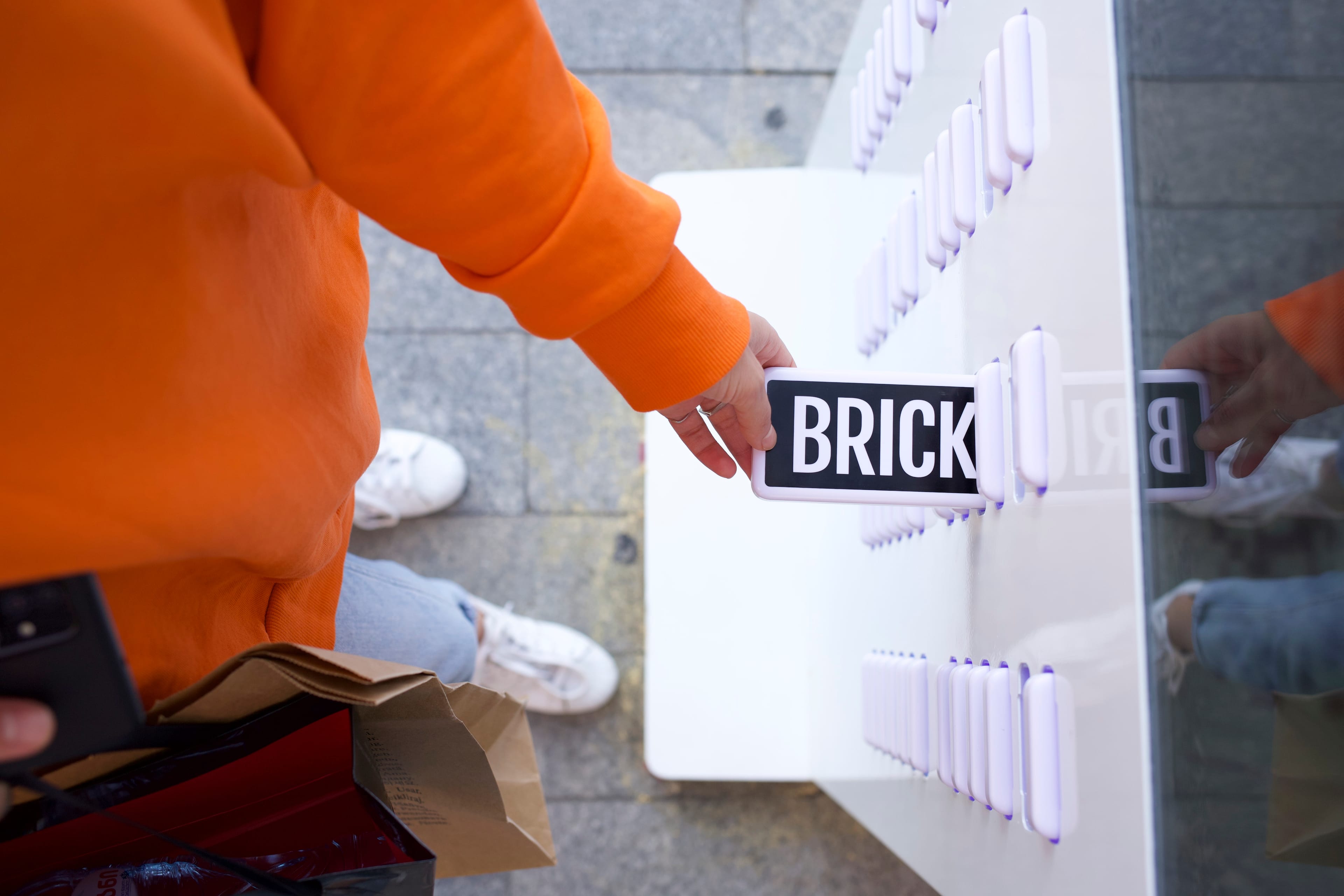 A hand retrieving a Brick powerbank from a station