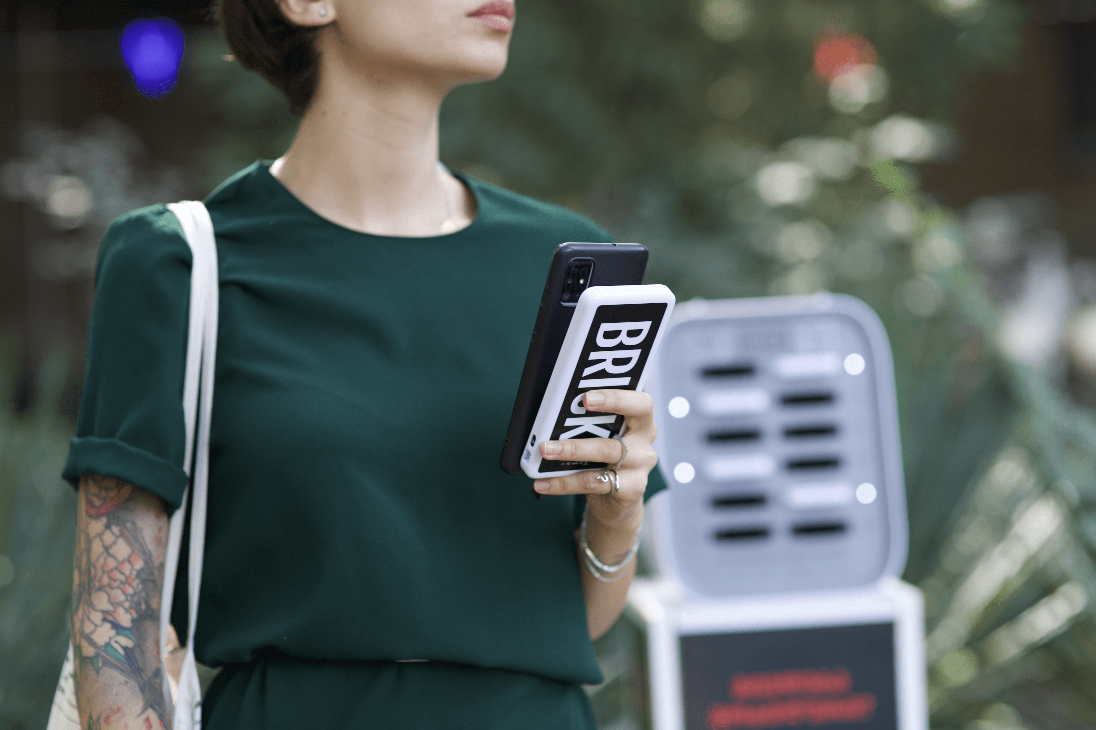 A woman holding a Brick powerbank in front of a rental station